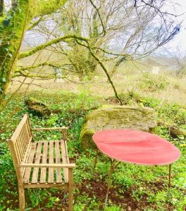 a table and a bench and a red table and chair at Manoir De Saint Ceran Au Royaume De Louango in Lanrivain