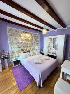 1 dormitorio con 1 cama grande y paredes moradas en Apartment Maris, en Dubrovnik