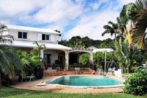 een huis met een zwembad in de tuin bij Villa Perroquet - vue mer - grande piscine chauffée in La Possession