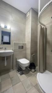 uma casa de banho com um WC, um lavatório e um chuveiro em Grey escape apartments em Qalḩāt