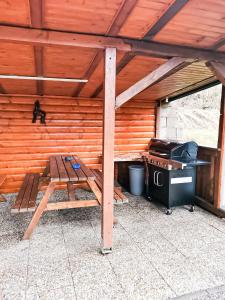 eine Holzhütte mit einem Herd und einem Picknicktisch in der Unterkunft Chata Daniela in Dedinky