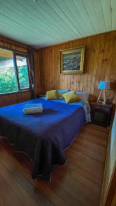 um quarto com uma cama azul num quarto de madeira em Casa Dalpa Pucón em Pucón