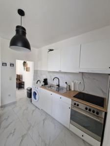 a white kitchen with a sink and a stove at Apartment SweetDreams in Bremerhaven