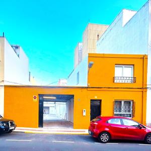 a red car parked in front of a yellow building at Benicasim Village in Benicàssim