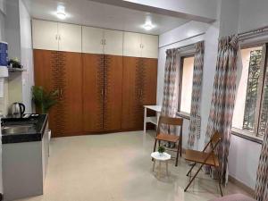 a kitchen with wooden cabinets and a table and chairs at Coral: Pvt Studio in Koregaon Park. WiFi SmartTv AC in Yeraoda +10 photos