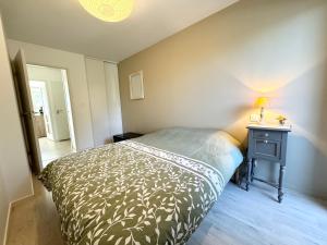 1 dormitorio con 1 cama y 1 mesa con lámpara en Bel appartement T3 de standing – proche de la mer, en Plouharnel