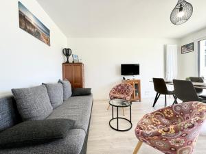 sala de estar con sofá gris y sillas en Bel appartement T3 de standing – proche de la mer, en Plouharnel