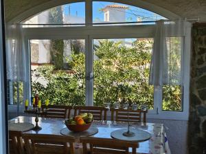 a table with a bowl of fruit in front of a window at Montagne vue panoramique sur mer in Pals