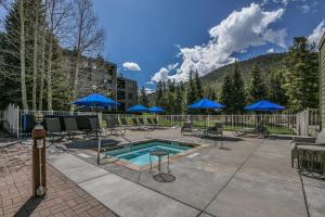 a pool with chairs and blue umbrellas on a patio at Lakeside 1496 in Keystone