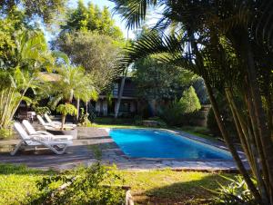 a swimming pool with two lounge chairs next to a house at Los Tangueros in Puerto Iguazú