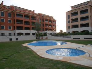 een vijver in het gras voor een gebouw bij Jardinas de les Marinas in Denia