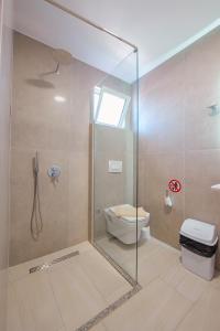 een badkamer met een glazen douche en een toilet bij Villa Family Garden in Ksamil