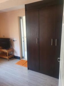 um quarto com duas grandes portas de madeira e uma televisão em Ludinz guest house na Cidade do Cabo