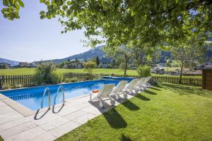 uma fila de cadeiras sentadas ao lado de uma piscina em Pension Sonnblick em Westendorf