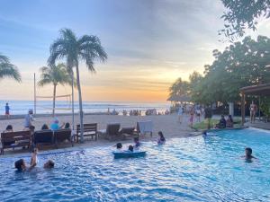 un grupo de personas en una piscina junto a la playa en Hacienda Iguana Surf & Golf, en Tola