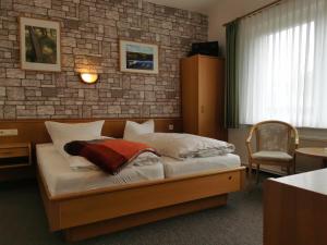 a bed in a room with a brick wall at Pension Am Strand in Juliusruh