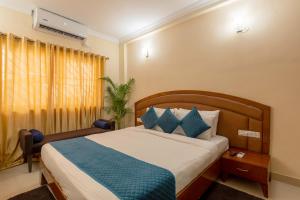 a bedroom with a large bed with blue pillows at Blue Bliss Hotel By PPH Living in Bangalore