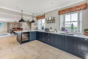 a kitchen with blue cabinets and a dining room at The Farmhouse in Ravensworth