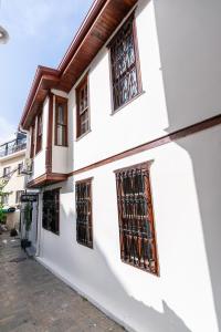 ein weißes Gebäude mit vergitterten Fenstern auf einer Straße in der Unterkunft BÜTÜNOĞLU PANSİYON in Antalya