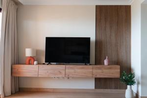 a television on a wooden entertainment center in a living room at Casa del Sol: Sunrise to Sunset in Sitio de Calahonda