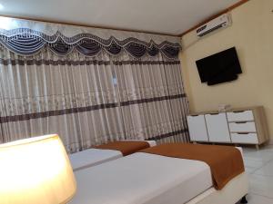 a hotel room with two beds and a television at H. V Hotel Bandara Gorontalo in Bongomeon