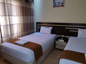 Dos camas en una habitación de hotel con dos en H. V Hotel Bandara Gorontalo en Bongomeon