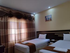 a hotel room with two beds and a window at H. V Hotel Bandara Gorontalo in Bongomeon