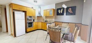 a kitchen with a white refrigerator and a table with chairs at Amdar Holiday Apartments in Eilat