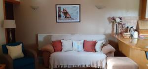 a white chair with pillows on it in a room at Henblas Holiday Cottages in Abergele
