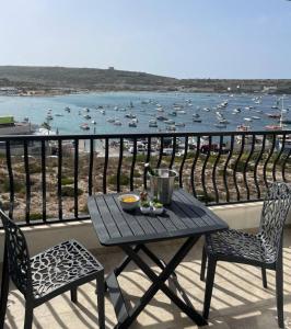 einen Tisch und Stühle auf einem Balkon mit Blick auf einen Wasserkörper in der Unterkunft Mellieha Bay Seafront 1bed Penthouse in Mellieħa