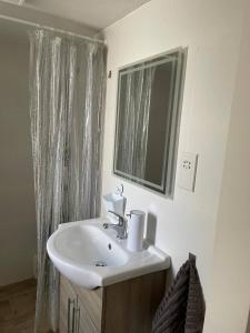ein Bad mit einem Waschbecken und einem Spiegel in der Unterkunft Mellieha Bay Seafront 1bed Penthouse in Mellieħa