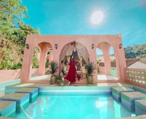 Malá home & coffee في دالات: امرأة بلبس احمر تقف في غرفة بجانب مسبح