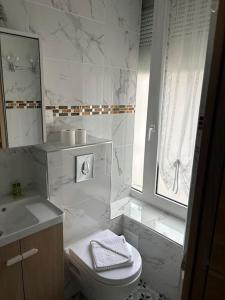 a white bathroom with a toilet and a sink at studio avec terrasse en face la gare d’Enghien a 15 minute de paris gare du nord et a 10 mn de stade de France in Enghien-les-Bains
