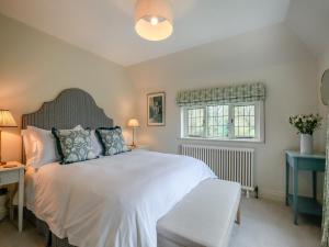 Un dormitorio con una gran cama blanca y una ventana en Keeds Cottage, en Pulborough