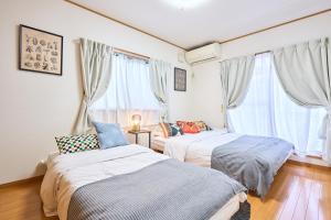 two beds in a room with two windows at Comfy Home Koiwa in Tokyo