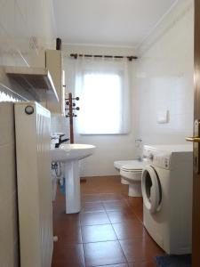 uma casa de banho branca com um lavatório e um WC em Cjase Paola em Cassacco