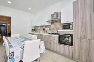 a kitchen with a table and a stove and a microwave at Seafront Townhouse in Birzebbuga in Birżebbuġa
