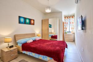 a bedroom with a bed with a red blanket at Seafront Townhouse in Birzebbuga in Birżebbuġa