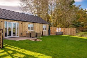 a garden with a wooden house and a lawn at Bearskin Cottage in Leyburn