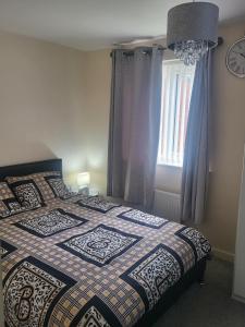 um quarto com uma cama com uma colcha e uma janela em Inviting 3-Bed House in Bolton em Bolton