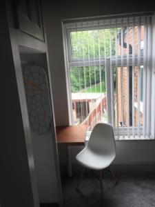 a white chair sitting in front of a window at 77 Underwood Lane in Crewe