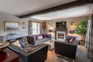 a living room with leather furniture and a fireplace at Sun Hill Farmhouse in Leyburn