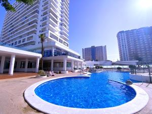 a large pool in front of a building with tall buildings at Tropicalidays Apartment Ocean Side Paraiso in Playa Paraiso