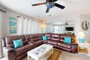 a brown leather couch in a living room with a ceiling fan at Tee Time Beach Time in Calabash