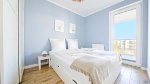 een witte slaapkamer met een wit bed en een raam bij Apartamenty Sun & Snow Gąski in Gąski