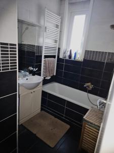 een zwart-witte badkamer met een wastafel en een bad bij Luxurious 2 in Brussel