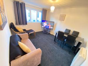 a living room with a couch and a tv and chairs at 2 Bedroom Modern Apartment in Earl Shilton