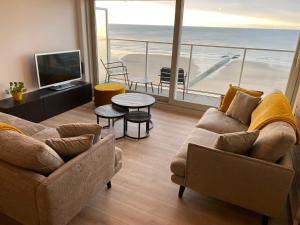 a living room with a couch and a tv and a balcony at Romanza Zeezicht in Middelkerke