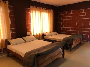 Gonikoppal的住宿－Hotel Chef Knife (Part of Querencia Precinct)，一间设有两张床和砖墙的房间