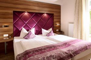 een slaapkamer met een groot bed met een paars hoofdeinde bij Arkona Strandresidenzen in Binz